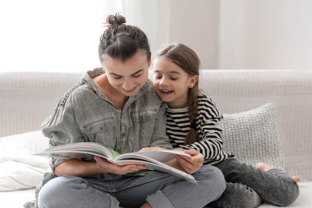 mom and daughter reading a book together while practicing reading comprehension strategies